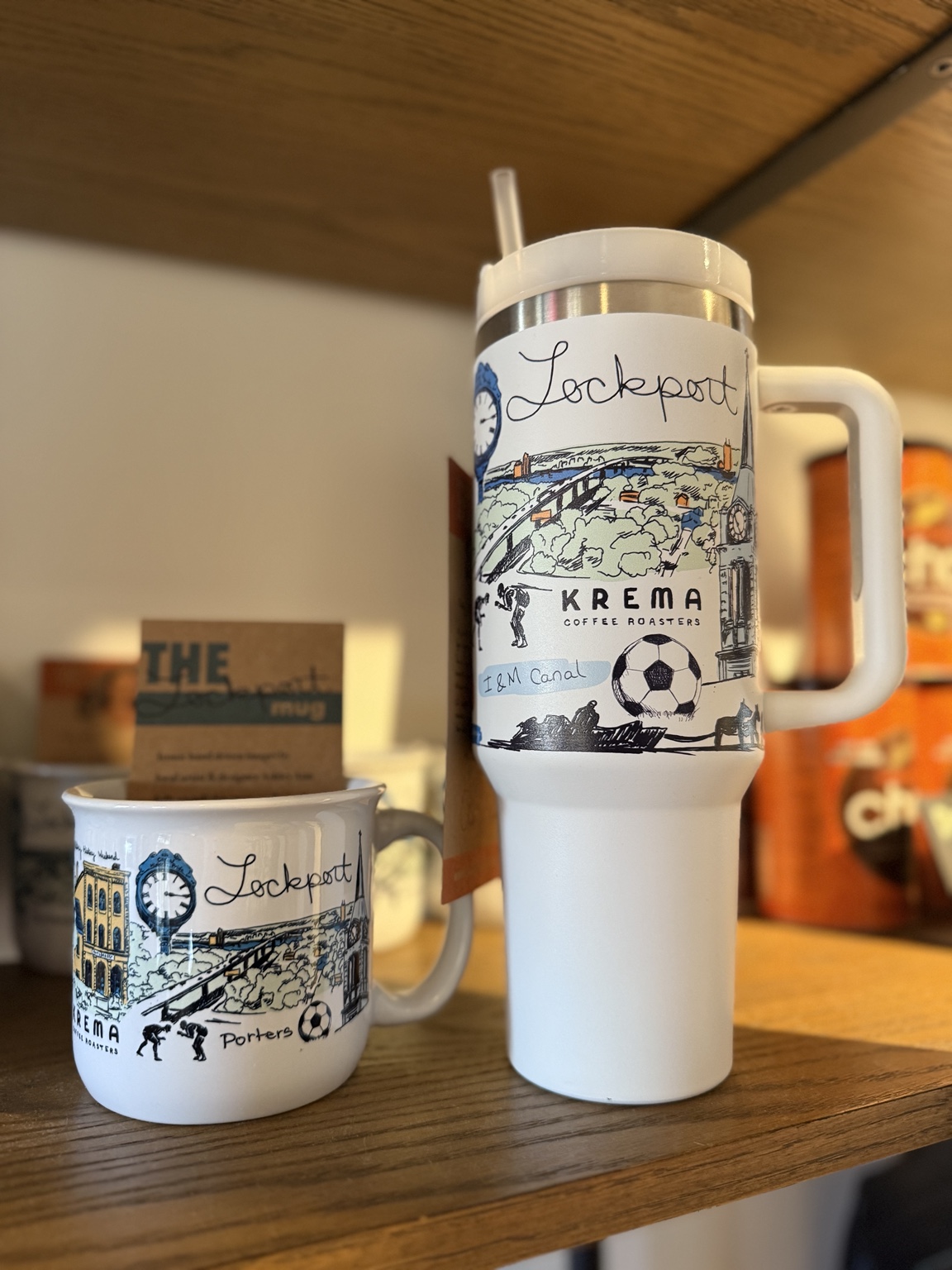 The hand-drawn Lockport mug and matching travel tumbler displayed at Krema Coffee